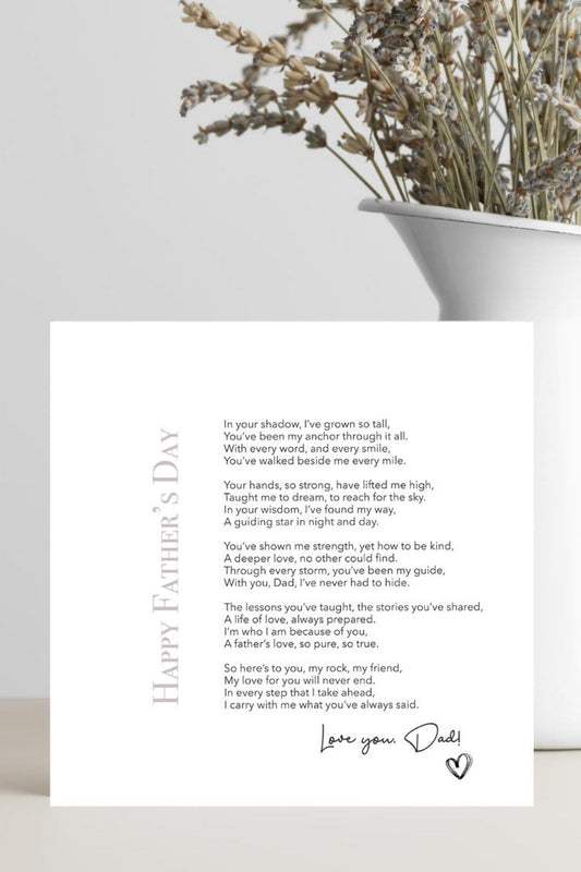 Greeting card with a Father's Day message on a white surface with a vase of dried flowers.