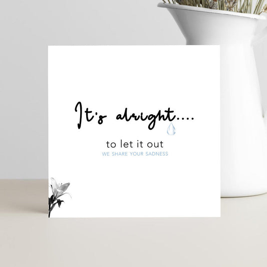 A simple, elegant condolence greeting card featuring the words “It’s Alright to Let It Out” in graceful script, resting on a soft neutral background with a calm and comforting mood.