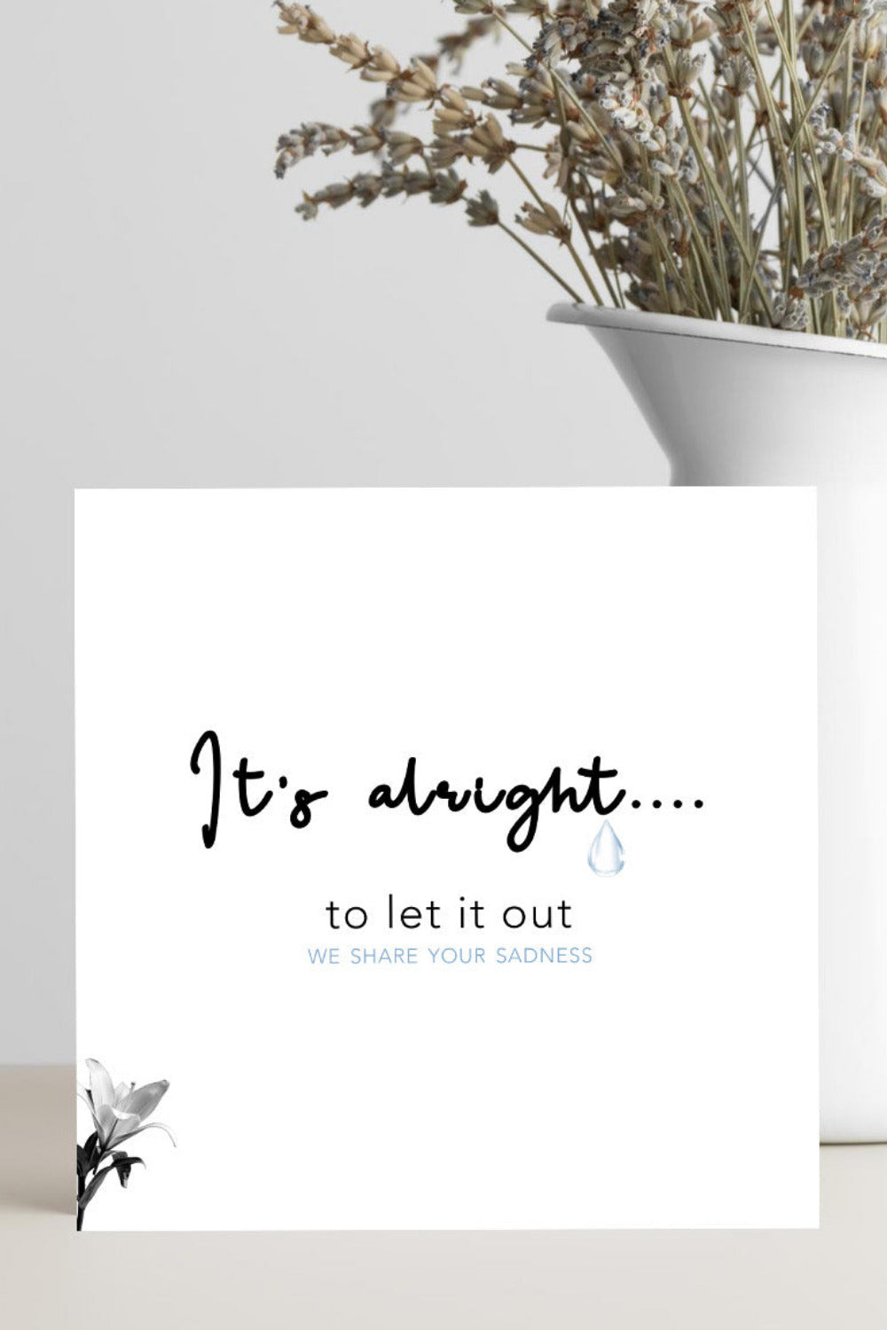 Motivational card with text 'It's alright... to let it out' on a white background with a vase of dried flowers.