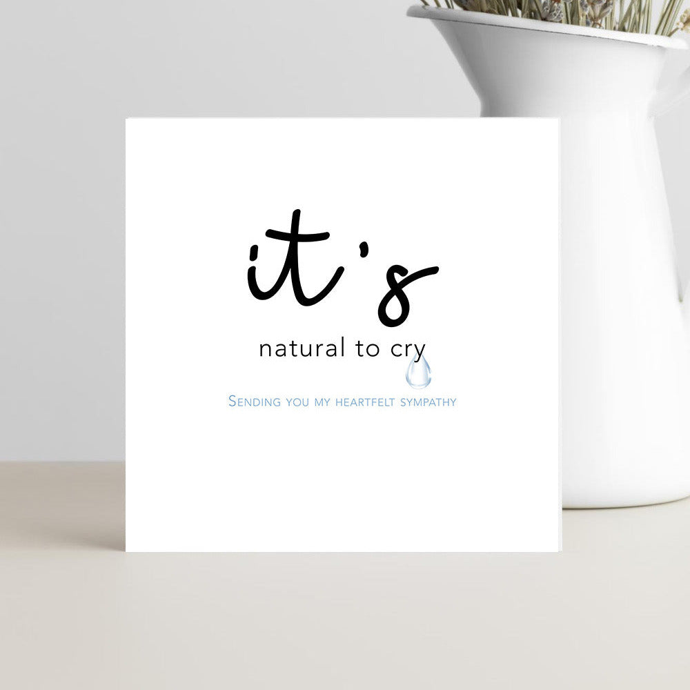 card featuring the words “It’s Natural to Cry” in graceful script, resting on a soft neutral background conveying calm, comfort, and compassion.