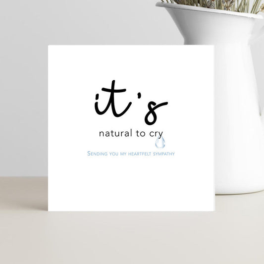 card featuring the words “It’s Natural to Cry” in graceful script, resting on a soft neutral background conveying calm, comfort, and compassion.