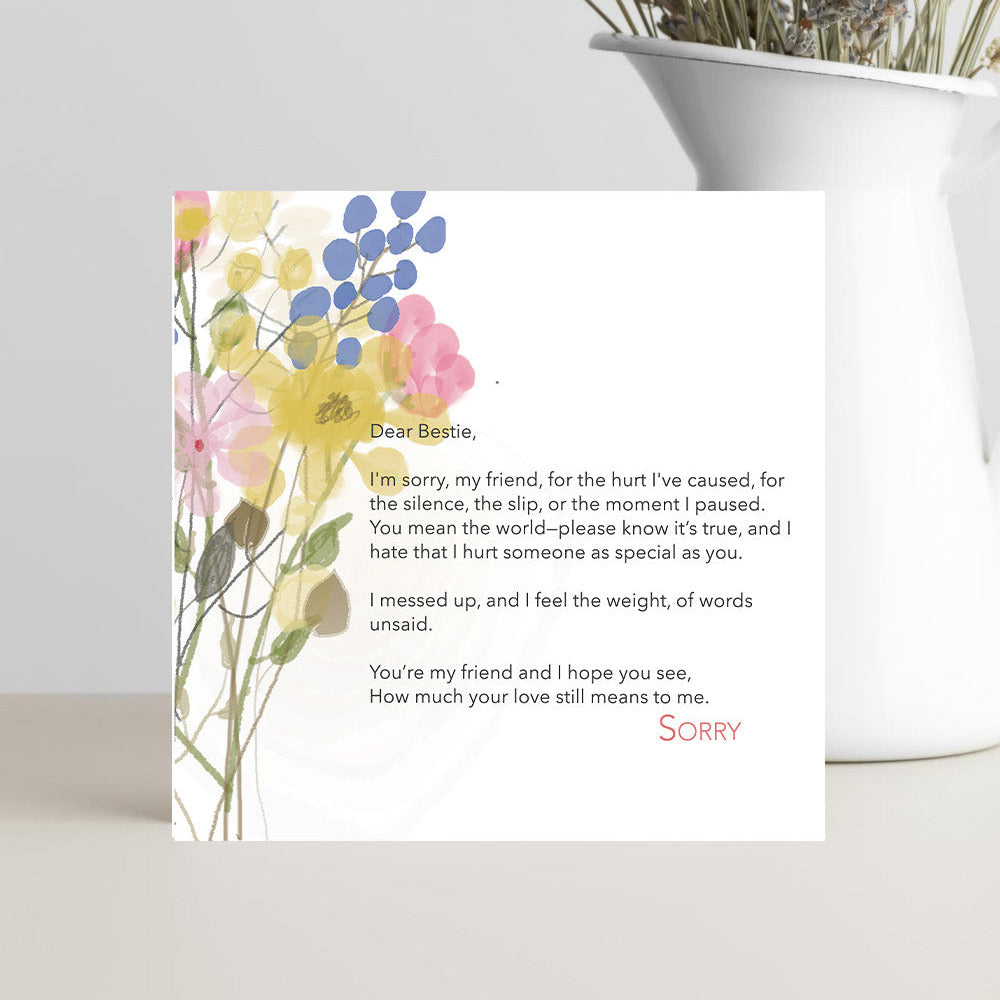 Greeting card with floral design and text on a white surface with a plant in the background
