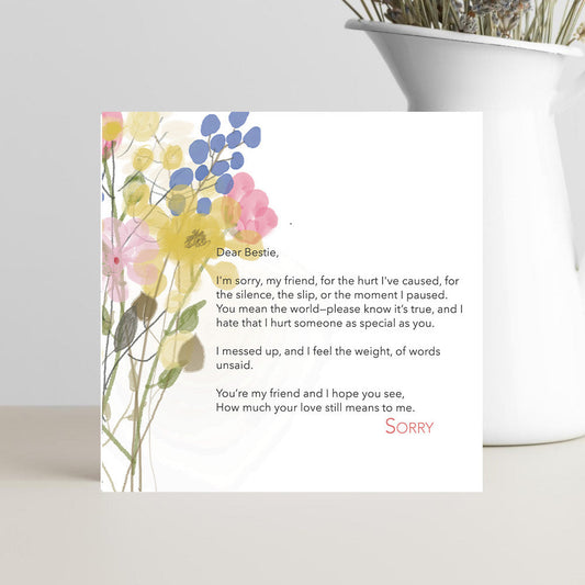 Greeting card with floral design and text on a white surface with a plant in the background