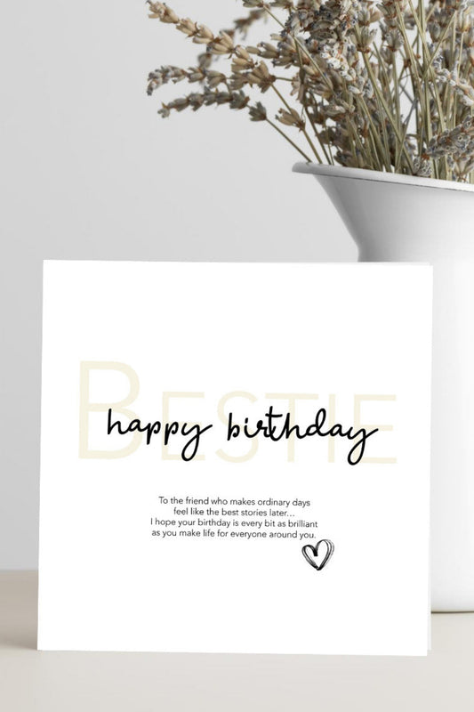White card with 'Happy Birthday' text on a white surface with a vase of dried flowers.