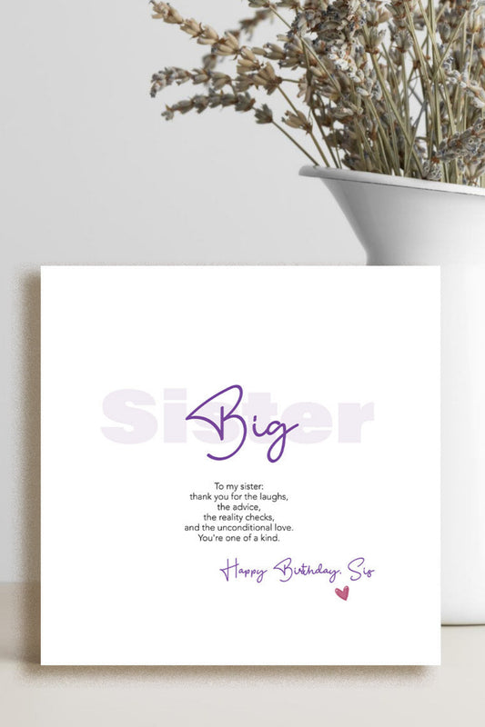 A square white birthday card with purple and gray text reading 'Big Sister' and 'Happy Birthday Sis,' styled on a light surface beside a white vase with dried flowers.
