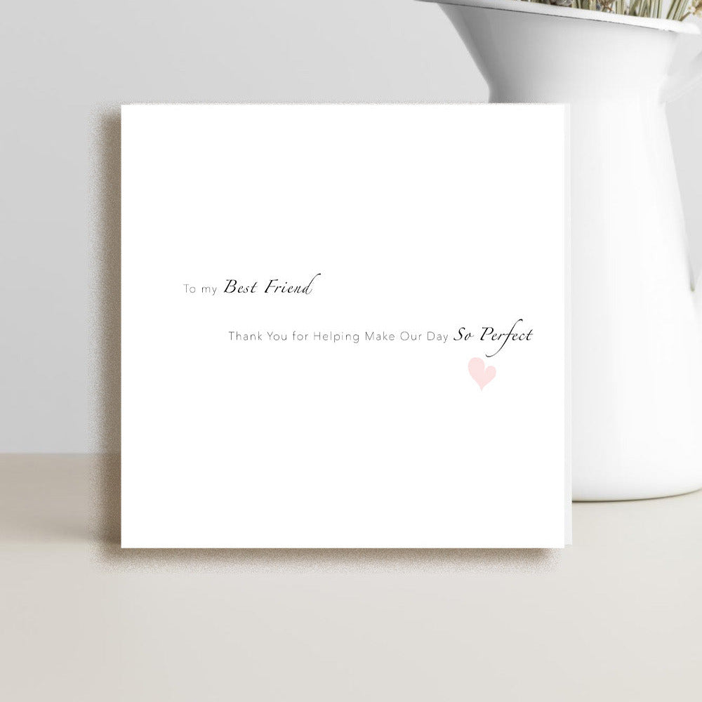 A square white greeting card with elegant black script text and a small pink heart