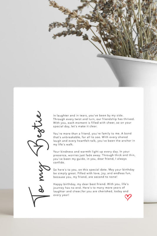 A white square card with a heartfelt birthday message addressed 'To my Bestie' in black script, placed on a light gray surface next to a white vase with dried branches.