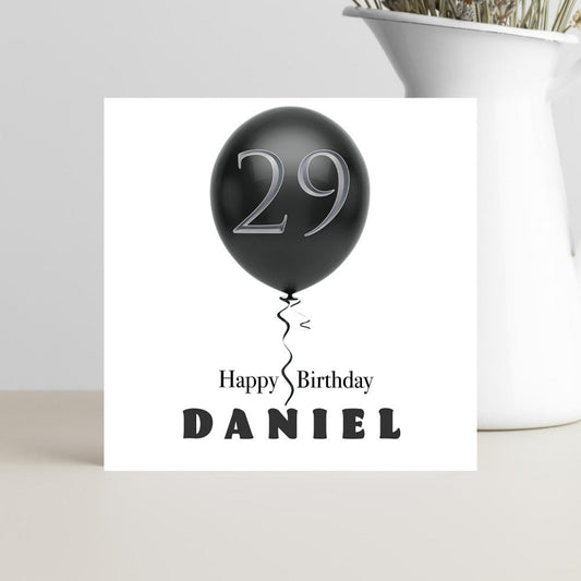 Greeting card with black balloon and 'Happy 29th Birthday Daniel' text on a white background.