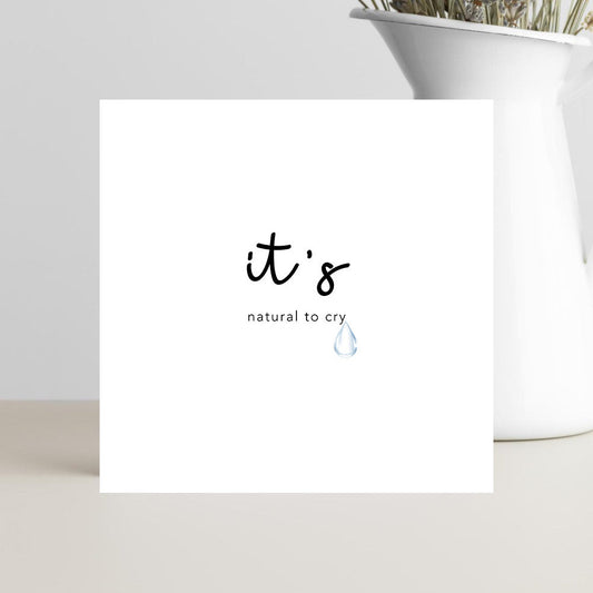 A simple, elegant condolence greeting card featuring the words “It’s Natural to Cry” in graceful script, resting on a soft neutral background conveying calm, comfort, and compassion.